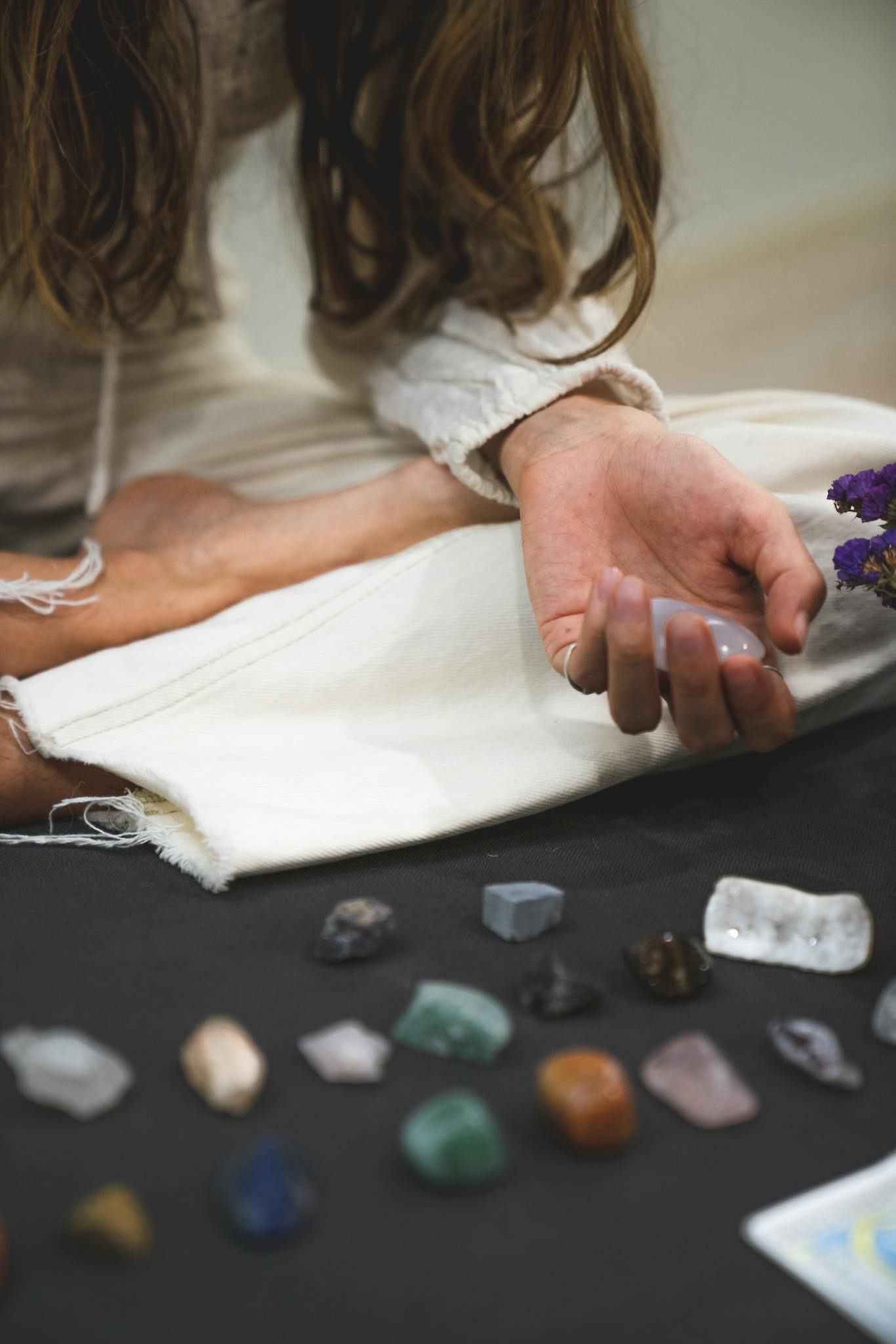 A person meditates with various healing crystals and stones, promoting tranquility and balance.